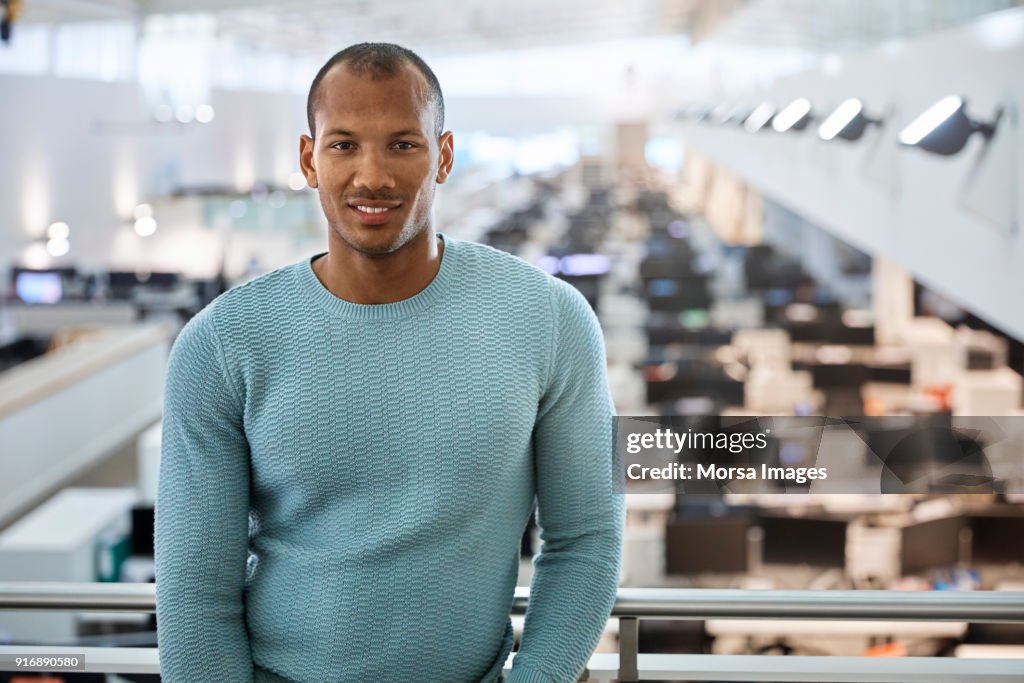 Confident young businessman standing at railing