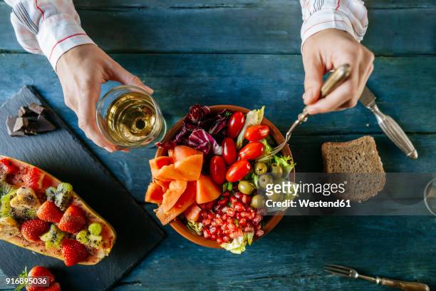 close-up of woman's hands eating salad wit tomato, pomegranate, papaya and olives, papaya with fruits and with wine glass - reglas de sociedad fotografías e imágenes de stock
