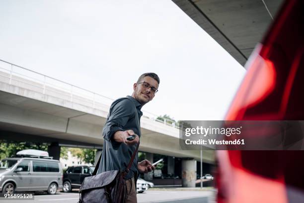 young businessman using remote control key of car - aparcamiento fotografías e imágenes de stock