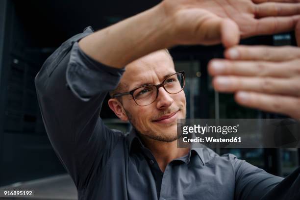portrait of smiling businessman making finger frame - fokussieren stock-fotos und bilder