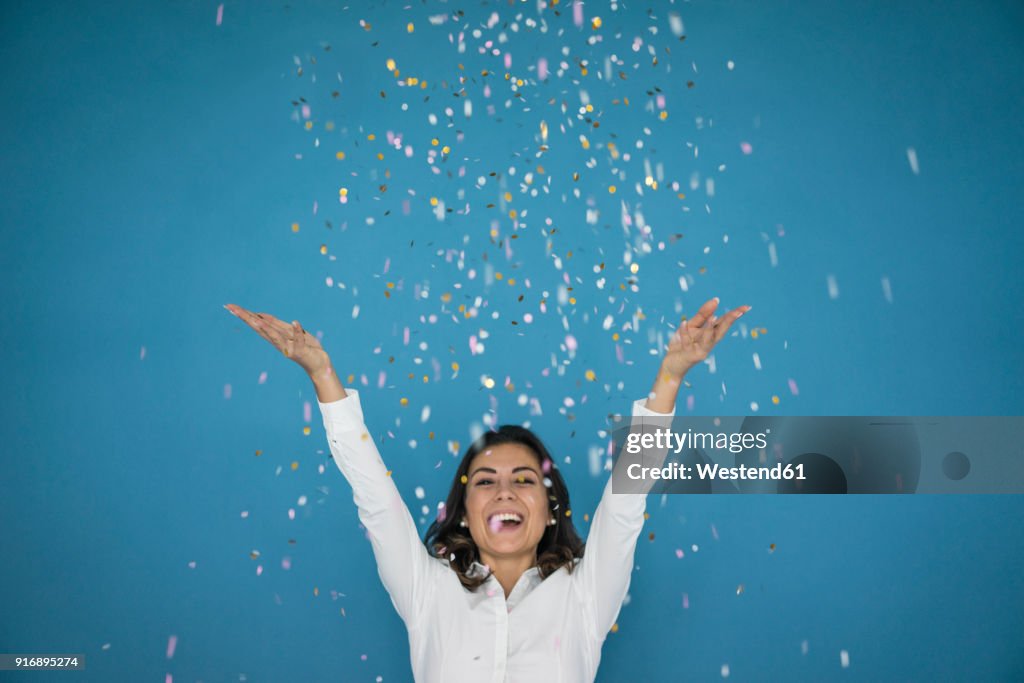 Portrait of laughing woman throwing confetti in the air