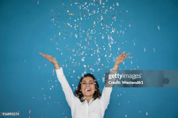 portrait of laughing woman throwing confetti in the air - blue confetti stockfoto's en -beelden