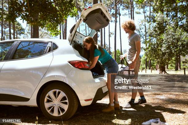 young couple loading a car in forest - arrival photos stock-fotos und bilder