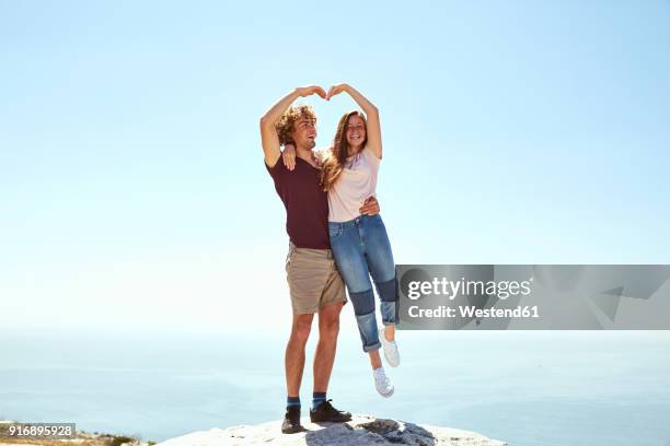 south africa, cape town, happy young couple on top of a mountain at the coast - young woman standing against clear sky スト�ックフォトと画像