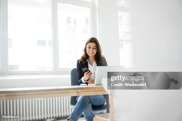 businesswoman sitting at desk in the office working on laptop - woman business desk front laptop office fotografías e imágenes de stock