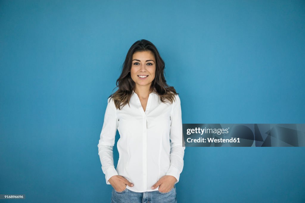 Portrait of smiling woman standing in front of blue wall