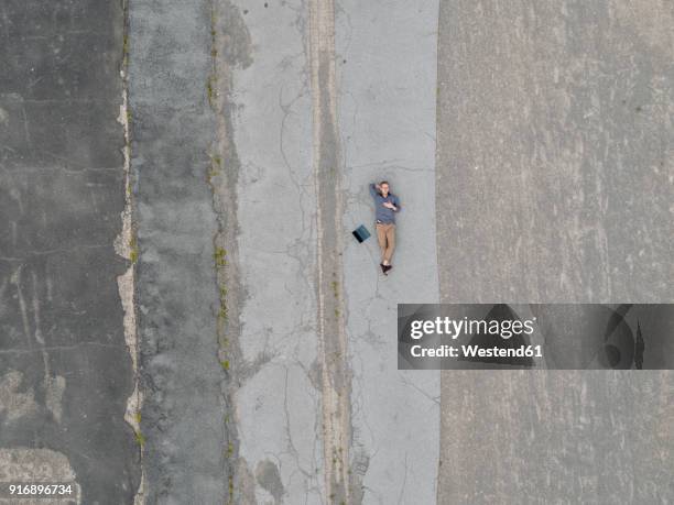 young businessman with laptop relaxing in solitude, quadcopter view - hände hinter dem kopf stock-fotos und bilder