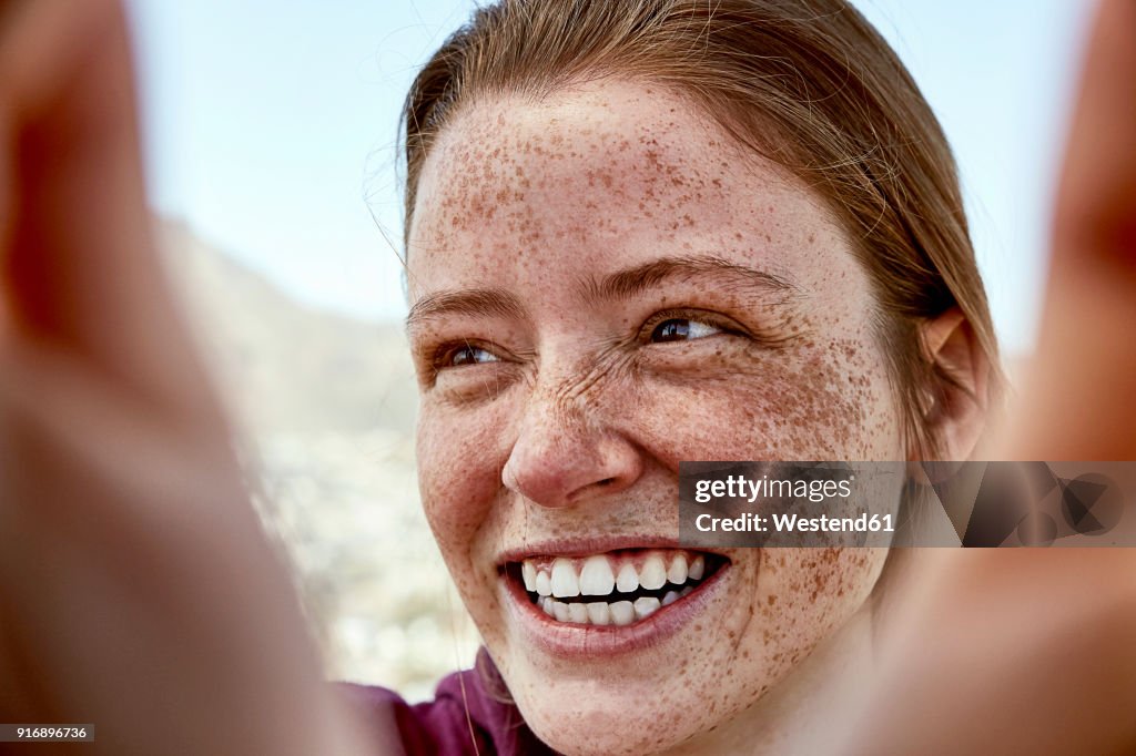 Portrait of laughing young woman with freckles outdoors