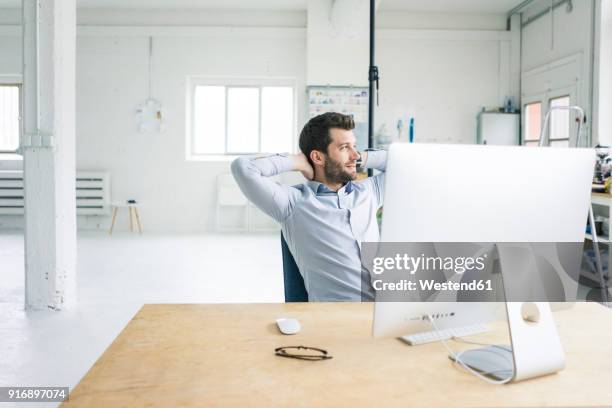 smiling businessman sitting at desk in office having a break - confident desk man text space stock pictures, royalty-free photos & images