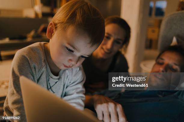 family using laptop on the couch in the dark - baby night stock-fotos und bilder