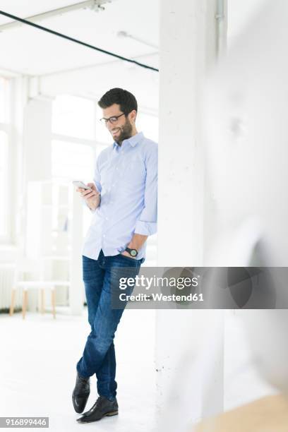 smiling businessman looking at cell phone in office - casual businessman glasses white shirt stock pictures, royalty-free photos & images