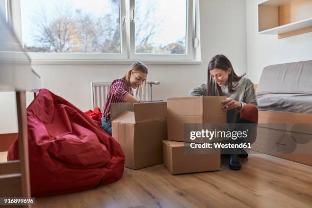 two young women unpacking cardboard boxes in a room - student flat stock pictures, royalty-free photos & images