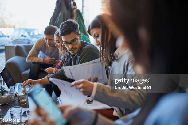 group of friends sitting together in a cafe with laptop and documents - founder stock pictures, royalty-free photos & images