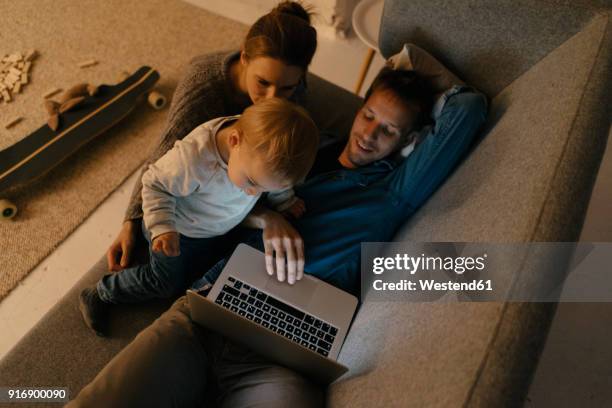 family using laptop on the couch in the dark - dark baby stock pictures, royalty-free photos & images