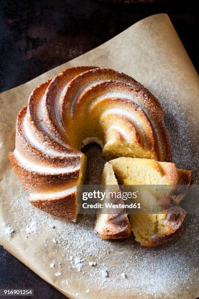 sliced gugelhupf sprinkled with icing sugar on parchment paper - tulbandcake stockfoto's en -beelden