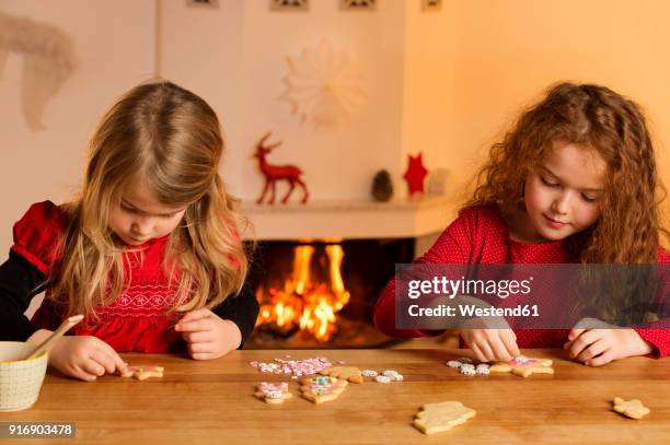 little girls garnishing christmas cookies with hundreds and thousands - kids advent stock pictures, royalty-free photos & images