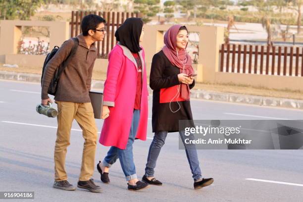 young girls in hijab (head scarf) and a boy walking and enjoying on the road - punjab pakistan 個照片及圖片檔