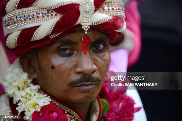 An Indian groom looks on during a mass wedding for members of the Adivasi Bhil tribal community in Ahmedabad on February 11, 2018. Some 35 couples...