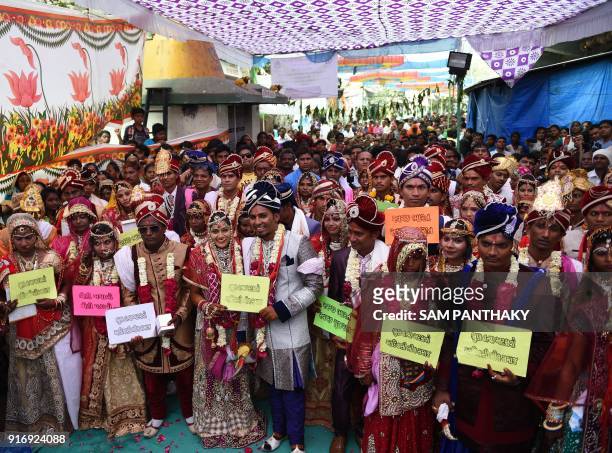 Indian couples pose for a photograph during a mass wedding for members of the Adivasi Bhil tribal community in Ahmedabad on February 11, 2018. Some...