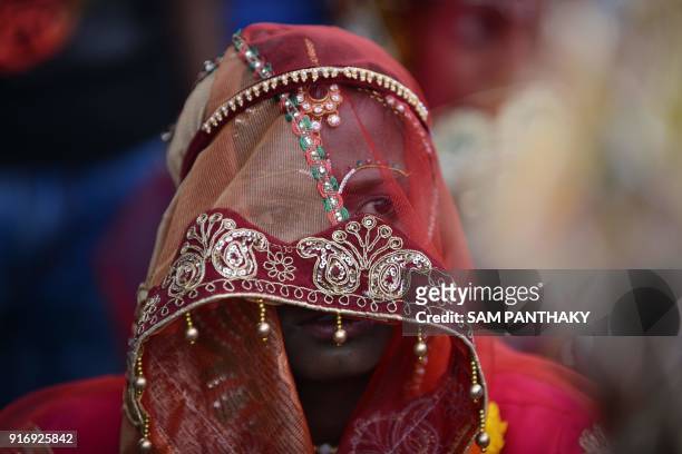 An Indian bride looks on during a mass wedding for members of the Adivasi Bhil tribal community in Ahmedabad on February 11, 2018. Some 35 couples...