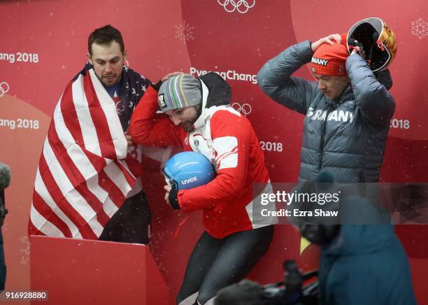 Chris Mazdzer of the United States, David Gleirscher of Austria and Johannes Ludwig of Germany react as they watch the final run of Felix Loch of...