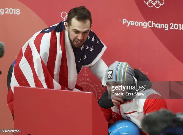 Chris Mazdzer of the United States and David Gleirscher of Austria react as they watch the final run of Felix Loch of Germany in the Luge Men's...
