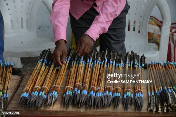 An Indian trader from Chota Udepur, a tribal dominated region of Gujarat, arranges bows and arrows for sale outside the venue of a mass wedding for...