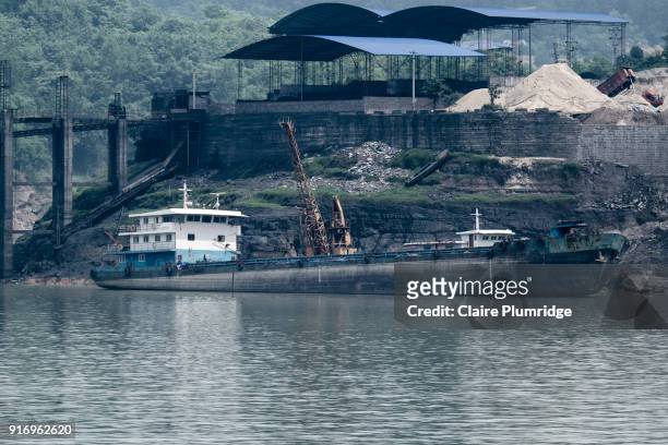 commercial ship with crane on, docked on the shore of the yangtze river, china. - claire plumridge fotografías e imágenes de stock