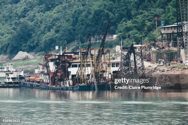 commercial ships with cranes on, docked on the shore of the yangtze river, china. - claire plumridge fotografías e imágenes de stock