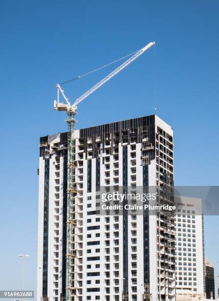 crane being used for in the construction of a building in dubai, uae, against a bright blue sky. - claire plumridge fotografías e imágenes de stock