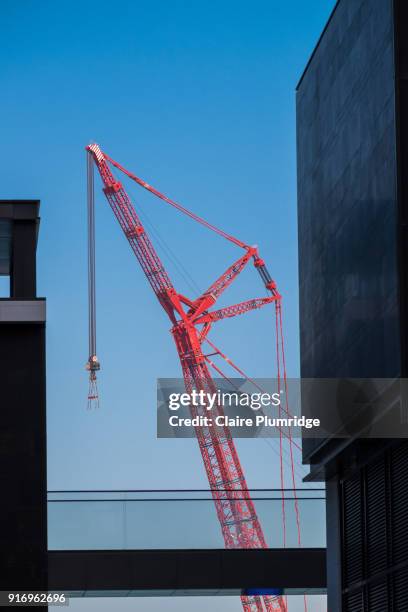 red construction crane - taken between two buildings in dubai, united arab emirates. - claire plumridge stock-fotos und bilder