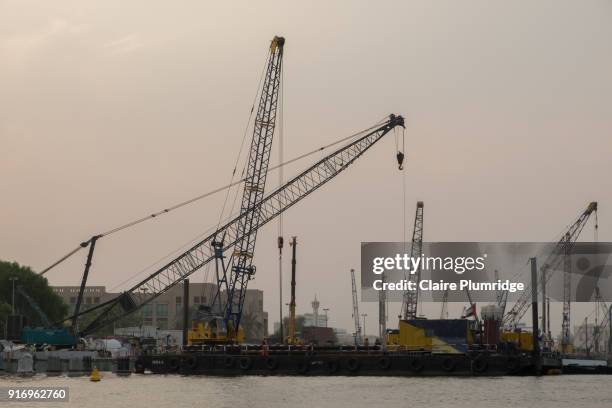 cranes loading and unloading from cargo ships, in dubai creek, united arab emirates. taken at dusk. - claire plumridge stock-fotos und bilder