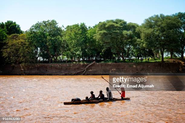 people crossing the omo river by local dug-out canoe, omo valley, ethiopia - december 13, 2017 - dugout canoe fotografías e imágenes de stock