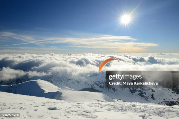 paragliding over snowcapped mountains and clouds - bansko stockfoto's en -beelden