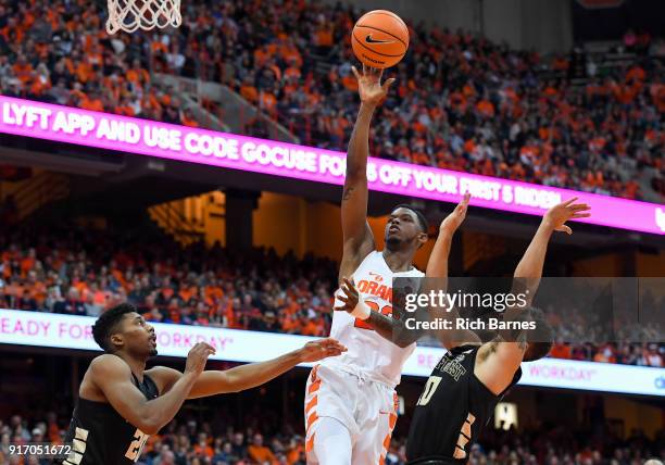 Frank Howard of the Syracuse Orange shoots the ball between Terrence Thompson and Mitchell Wilbekin of the Wake Forest Demon Deacons during the...