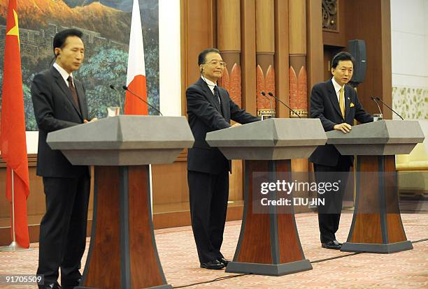 Japanese Prime Minister Yukio Hatoyama answers questions as Chinese Premier Wen Jiabao and South Korean President Lee Myung-Bak listen during a joint...