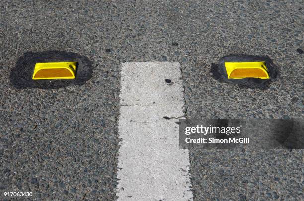 white dividing line and yellow plastic road reflectors on a city street - reflector stock pictures, royalty-free photos & images