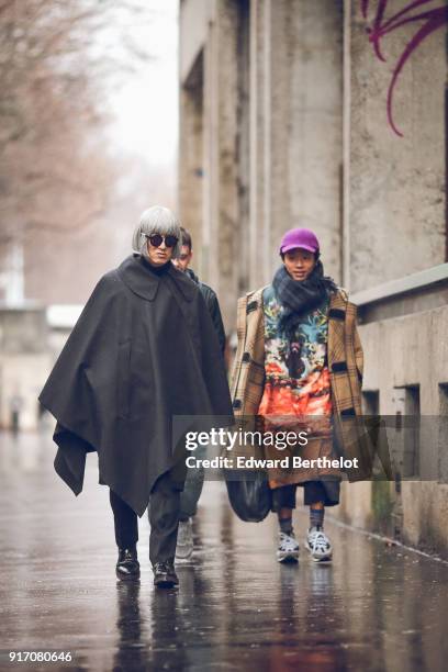 Guest wears sunglasses, a black cape, under the rain, outside Paul Smith, during Paris Fashion Week - Menswear Fall Winter 2018-2019, on January 21,...