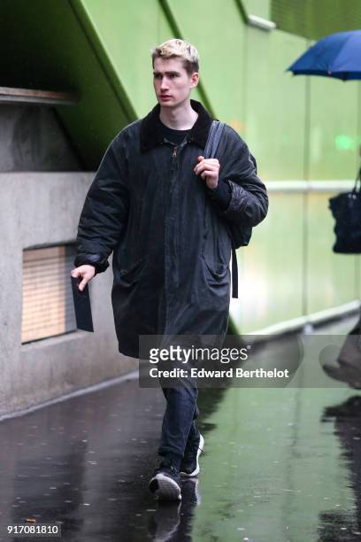 Guest wears a coat, under the rain, outside Paul Smith, during Paris Fashion Week - Menswear Fall Winter 2018-2019, on January 21, 2018 in Paris,...