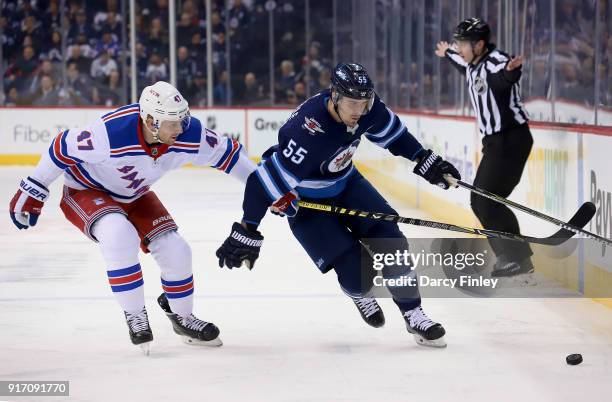 Mark Scheifele of the Winnipeg Jets plays the puck past a defending Steven Kampfer of the New York Rangers during first period action at the Bell MTS...