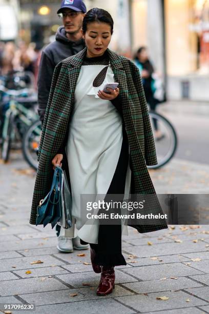 Guest wears a green checked coat, a white dress, outside Koche, during Paris Fashion Week Womenswear Spring/Summer 2018, on September 26, 2017 in...
