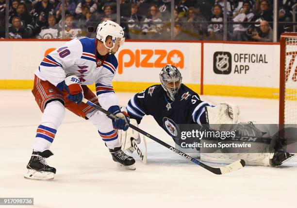 Winnipeg Jets Goalie Connor Hellebuyck forces New York Rangers Left Wing Michael Grabner to shoot over the net during a NHL game between the Winnipeg...