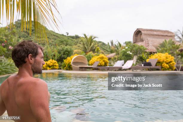 man sitting on pool edge - クタ ストックフォトと画像