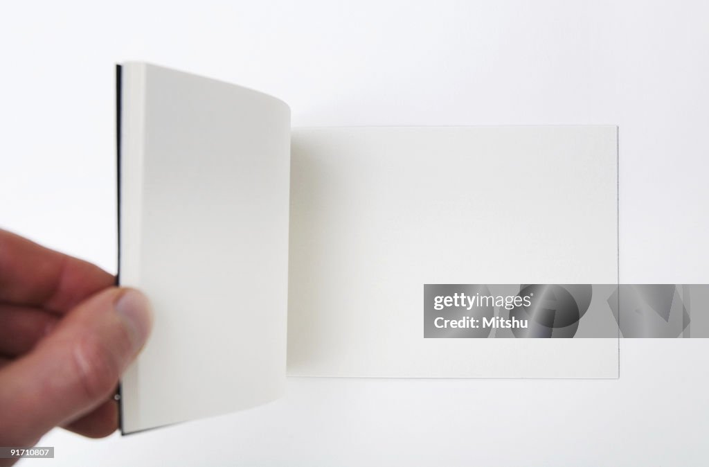 Open empty white book - Hand flipping pages.