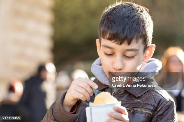 young boy eating icecream outdoors - anna pekunova stock-fotos und bilder