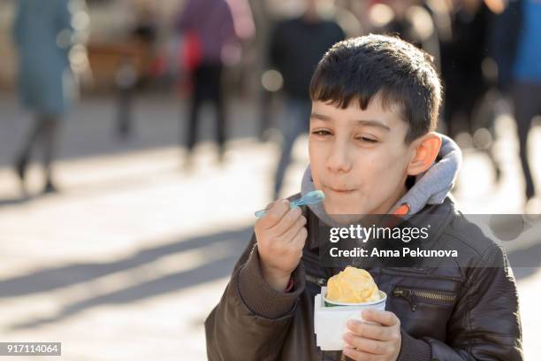 semi profile of young boy eating ice-cream - anna pekunova stock-fotos und bilder
