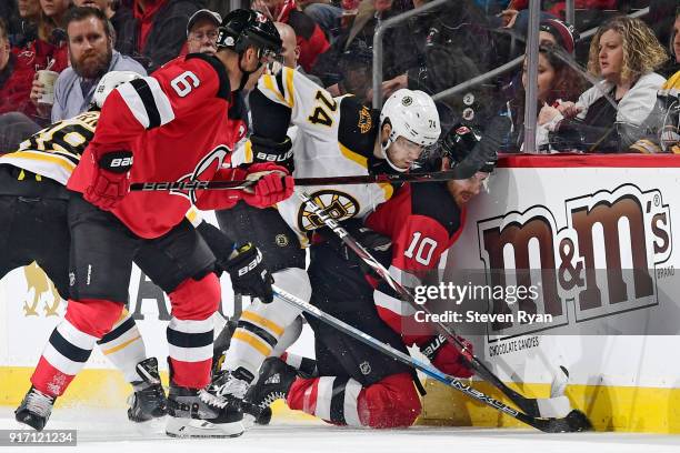 Jake DeBrusk of the Boston Bruins and Jimmy Hayes of the New Jersey Devils battle for the puck during the second period at Prudential Center on...