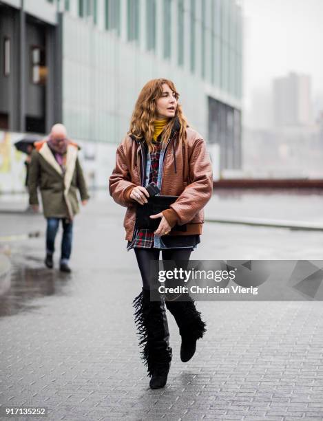 Ece Sukan wearing Supreme hoodie, brown leather jacket, plaid button shirt, black overknees with fringes seen outside Tibi on February 11, 2018 in...