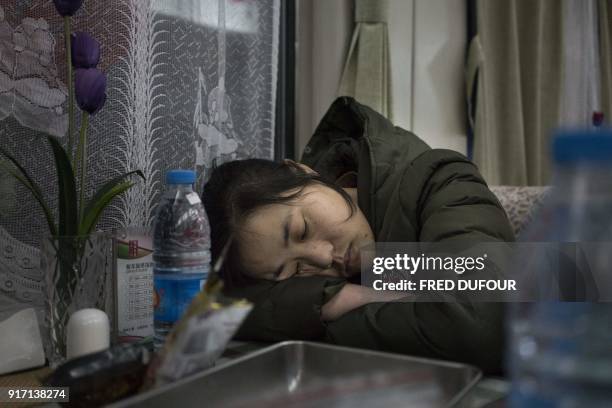 This photo taken on February 10, 2018 shows people sleeping in the restaurant car during the 26-hour train journey from Beijing to Chengdu, in...