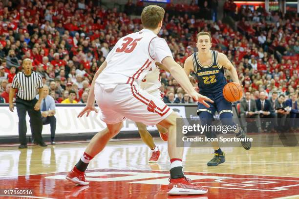 Michigan guard Duncan Robinson looks for an opening around Wisconsin forward Nate Reuvers during a college basketball game between the University of...